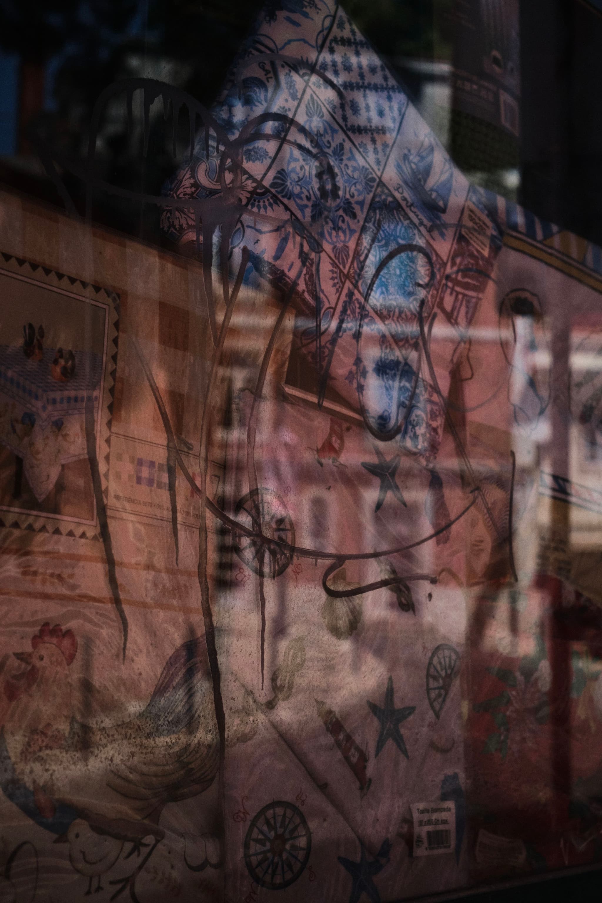 A complex reflection on a glass surface, blending images of architectural elements and various illustrations, including stars and abstract designs