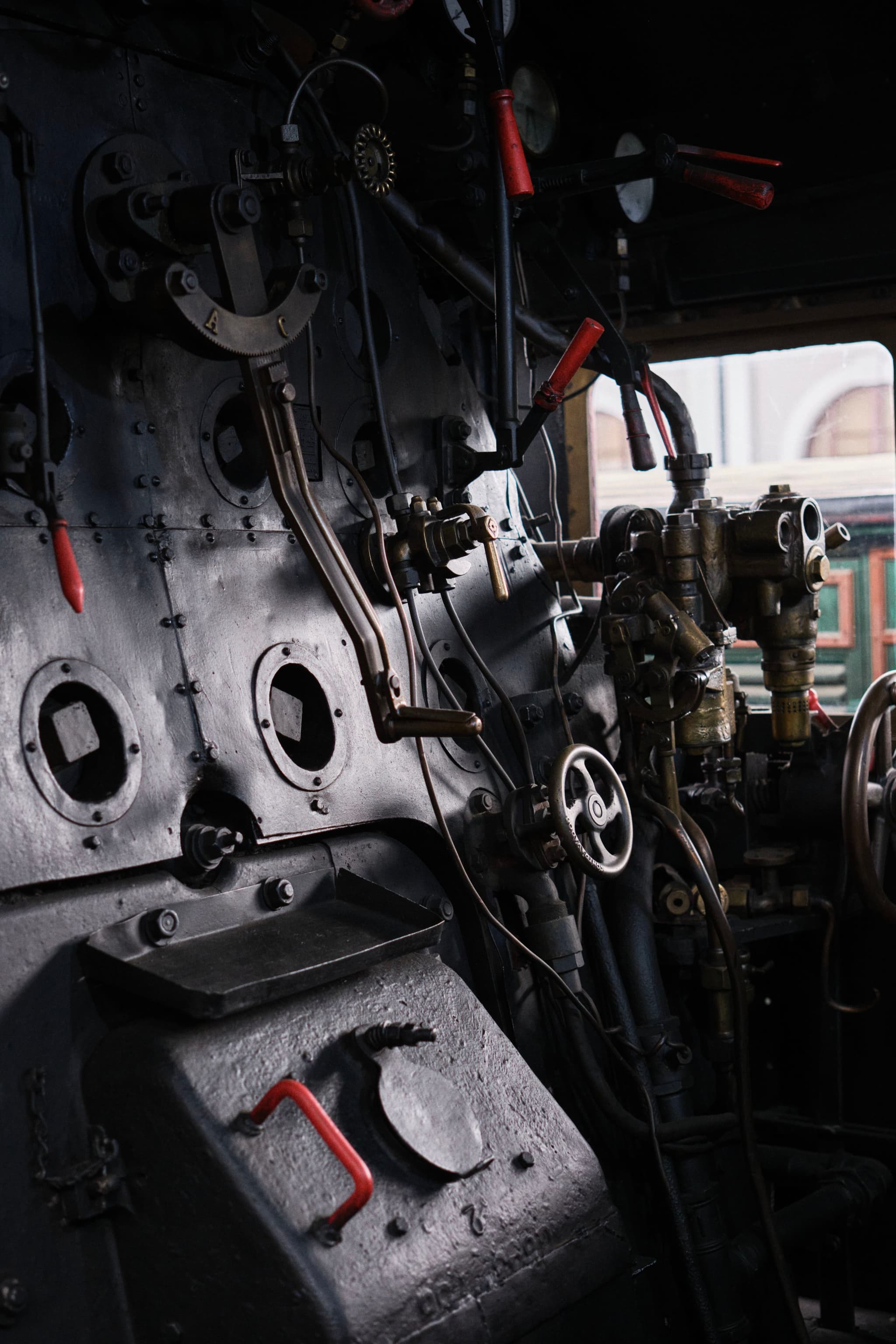 The interior of a vintage steam locomotive cab with various levers, gauges, and valves