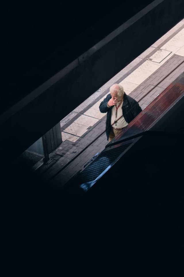 A person standing on a platform, viewed from above, with dark shadows framing the scene