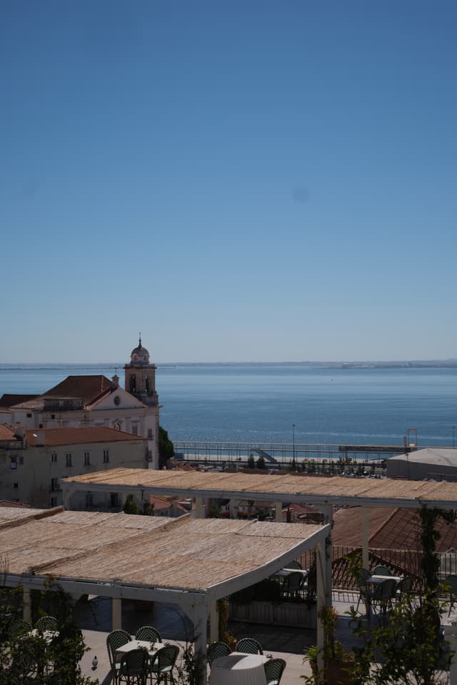 A coastal view with a church, rooftops, and a clear blue sky overlooking a calm sea