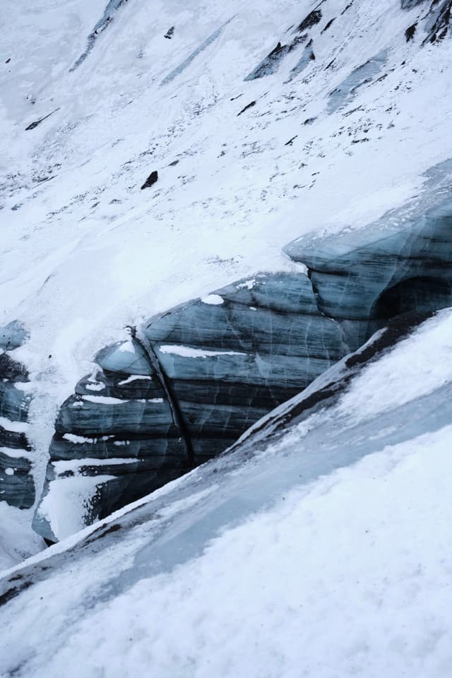 A snow-covered glacier with visible layers of ice and crevices